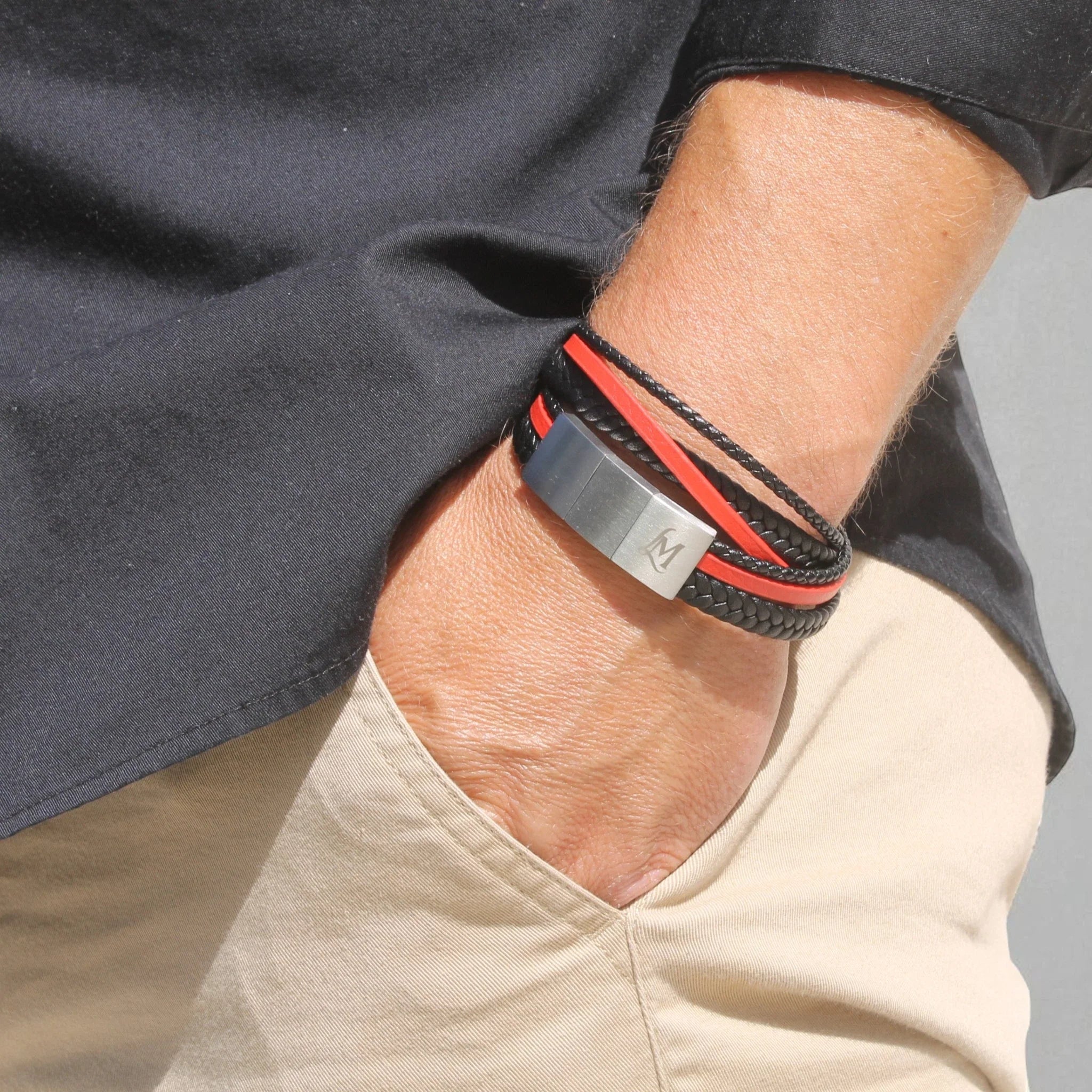 Poignet masculin portant un bracelet cuir tressé noir MenacL, assorti à une chemise claire et une veste casual, ambiance lifestyle urbaine.