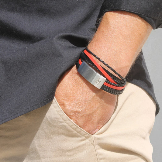 Poignet masculin portant un bracelet cuir tressé noir MenacL, assorti à une chemise claire et une veste casual, ambiance lifestyle urbaine.